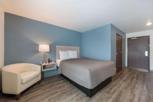 a blue bedroom with a bed and a chair at WoodSpring Suites Concord-Charlotte Speedway in Concord