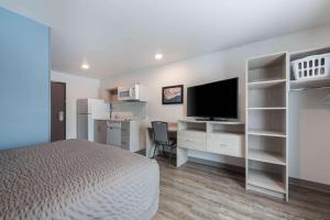 a bedroom with a bed and a desk with a television at WoodSpring Suites Concord-Charlotte Speedway in Concord