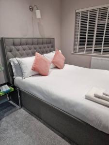 Una cama con almohadas rosas y blancas. en Beautiful and modern House in Gravesend, en Gravesend