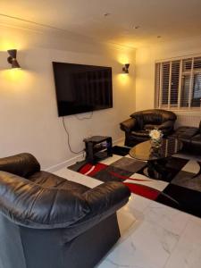 a living room with leather furniture and a flat screen tv at Beautiful and modern House in Gravesend in Gravesend