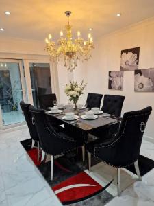 a dining room table with black chairs and a chandelier at Beautiful and modern House in Gravesend in Gravesend