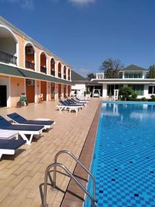 a large swimming pool with lounge chairs next to a building at Aurora Resort Khao Yai in Mu Si