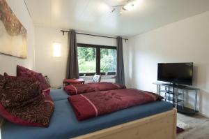 Schlafzimmer mit einem Bett mit roter Bettwäsche und einem TV in der Unterkunft Pension-Werdohl in Werdohl