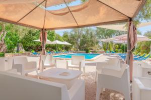 een zwembad met witte stoelen, tafels en parasols bij Els Marsals in Llucmajor