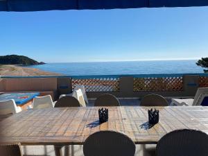 - une table en bois avec des chaises et une vue sur l'océan dans l'établissement Residence Fium Del Cavo, à Sainte-Lucie de Porto-Vecchio