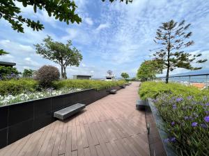 a walkway with benches in a garden with flowers at Luxury 2-Bedroom Condo with Pool in Chiang Mai