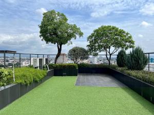 a rooftop garden with grass and trees on a building at Luxury 2-Bedroom Condo with Pool in Chiang Mai