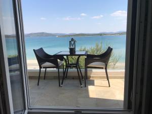 een tafel en stoelen op een balkon met uitzicht op de oceaan bij Villa Danica Murter in Betina
