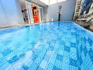 een zwembad met blauwe tegels op de vloer bij Rumah Kartika Batu in Batu