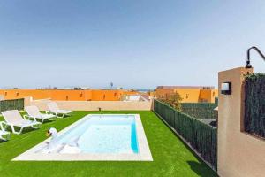 un patio trasero con piscina y césped verde en Villa Sunrise, en La Guirra