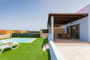 un patio trasero con piscina y césped verde en Villa Sunrise, en La Guirra