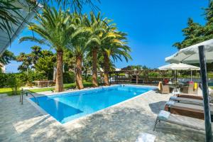 a swimming pool with palm trees in a resort at Albero Villa Polychrono in Polykhrono