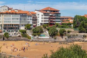 un grupo de personas en una playa con edificios en Antigua casa de escritor junto a la playa en Mundaka