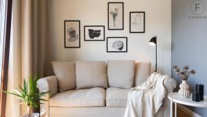 a living room with a couch and framed pictures on the wall at Flatbook - City Center SPA Apartments Toruńska in Gdańsk