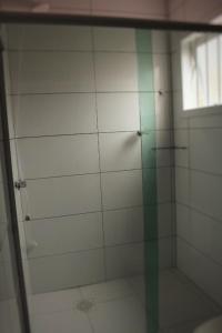 ducha con puerta de cristal y ventana en Casa Bellatorres en Passo de Torres