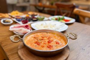 a bowl of soup on a wooden table with plates of food at Azalea Mansion Oldcity in Istanbul