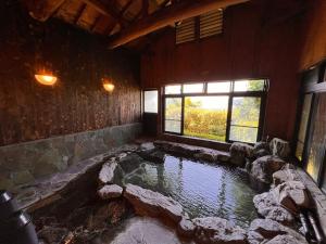 una gran piscina de agua en una habitación con rocas en 湯布院 星の里 Yufuin Hoshinosato en Yufuin