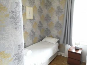 a bedroom with a bed and a wall with wallpaper at Portum -John St Apartment in Helensburgh