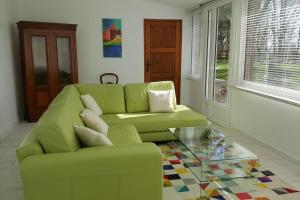 - un salon avec un canapé vert et une table en verre dans l'établissement La Bocagère d' Henri, à Saint-Côme-du-Mont