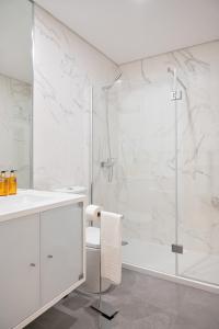 a white bathroom with a shower and a sink at Palmeiras Apartment, by Bolhão Residences in Porto