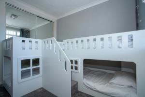 a bedroom with white bunk beds and a mirror at Botany Bay Holiday House - Family friendly, 50M from the beach in Kent