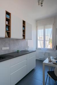 cocina con armarios blancos, mesa y ventana en Sunhill Studio en Budapest