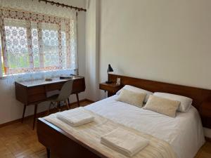 een slaapkamer met een bed, een bureau en een raam bij Moradia com Alma Xico's House in Coimbra