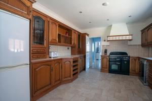 a large kitchen with wooden cabinets and black appliances at Botany Bay Holiday House - Family friendly, 50M from the beach in Kent