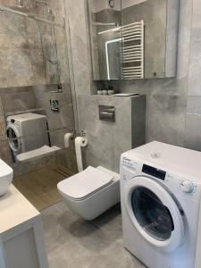 a bathroom with a washing machine and a toilet at Platinum De Lux Apartament in Stargard