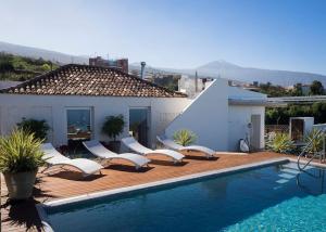 una piscina con sillas blancas y una casa en Casa Viña: a spectacular away from it all holiday, en La Orotava