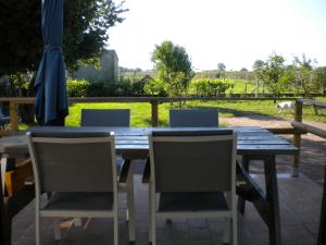 una mesa de madera con 4 sillas y una sombrilla en a l'orée de tronçais, en La Perche