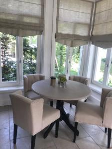 einen Tisch und Stühle in einem Zimmer mit Fenstern in der Unterkunft Villa Park Wisełka Spa & Wellness in Wisełka