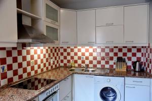 a kitchen with white cabinets and a sink and a washing machine at Cozy 2 Bedroom Apartment in Antique Bizanti Palace in Kotor