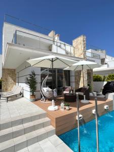 a house with a swimming pool and a patio with an umbrella at Luxury Villa4you in Los Alcázares