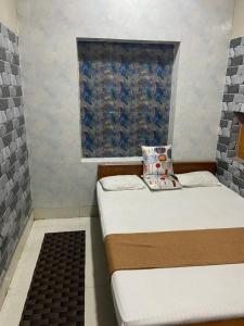 Duas camas num pequeno quarto com uma janela em Suraj Bhawan em Gaya