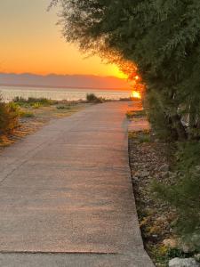 an empty road with the sunset in the background at Apartmani Sirius in Silba