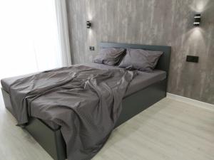 a bed with a gray comforter in a bedroom at Люкс Апартаменты Gray Pearl на Подолье in Vinnytsya
