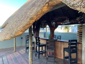 a bar with chairs and a straw roof at Almina villa in Windhoek