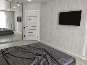 a bedroom with a bed and a television on the wall at Люкс Апартаменты Gray Pearl на Подолье in Vinnytsya