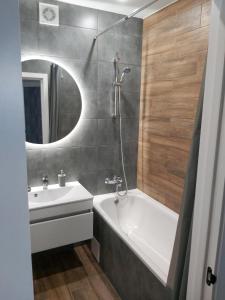 bagno con lavandino, vasca e specchio di Люкс Апартаменты Gray Pearl на Подолье a Vinnycja