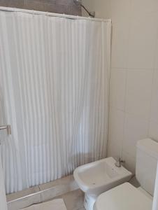 ein weißes Bad mit einem Duschvorhang und einem WC in der Unterkunft DEPARTAMENTOS LEMOS in Mendoza