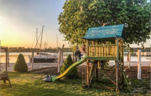 a playground with a tree and a slide at Gorgeous Home In Rydzewo With House Sea View in Rydzewo