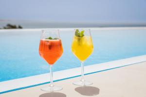 two wine glasses sitting on a table next to a pool at Vila Maria Hotel - Adults Only in Albufeira