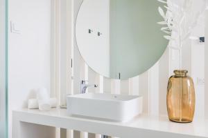 a white bathroom with a sink and a mirror at Vila Maria Hotel - Adults Only in Albufeira
