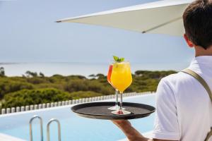 a man is holding a tray with a drink on it at Vila Maria Hotel - Adults Only in Albufeira