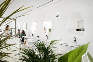 a restaurant with white tables and potted plants at Vila Maria Hotel - Adults Only in Albufeira