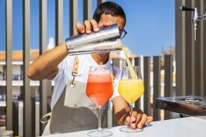 a man pouring a drink into a glass at Vila Maria Hotel - Adults Only in Albufeira