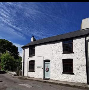 a white building with a door on a street at Glan-Yr-afon cottage two bedrooms in Sennybridge