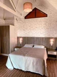 una camera con un grande letto e un muro di mattoni di Hotel Pousada Água Da Mina a Monte Sião