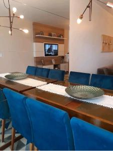 mesa de comedor con sillas azules y TV en Apê aconchegante e quentinho em São Joaquim, en São Joaquim